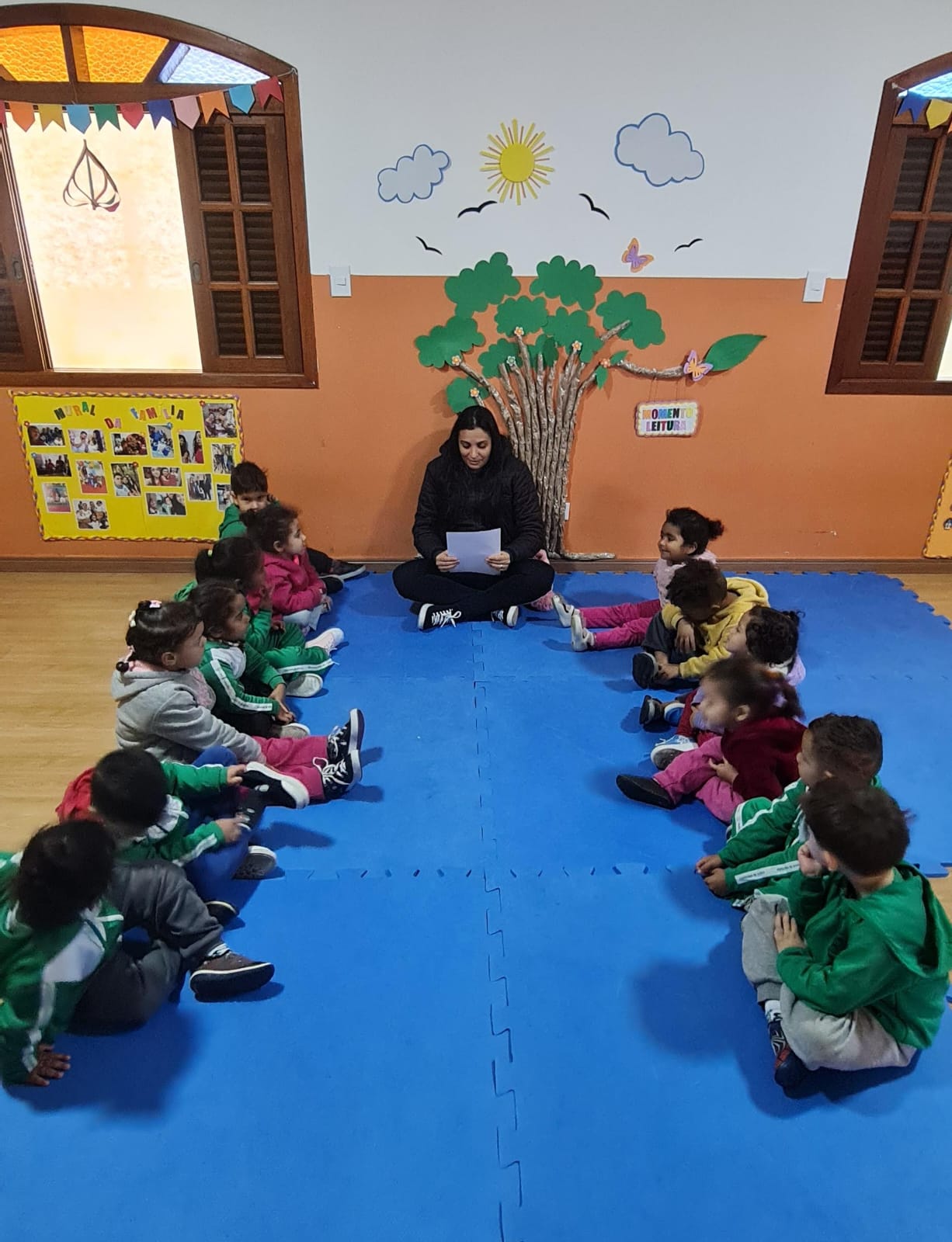 Roda de leitura com as crianças sentadas no tatame