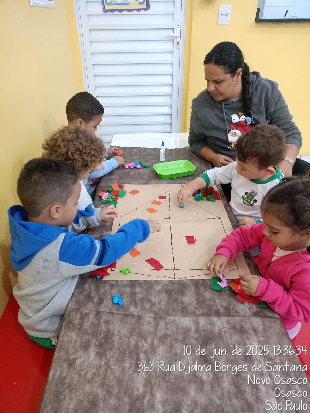 Atividade coletiva de colagem em mesa da creche